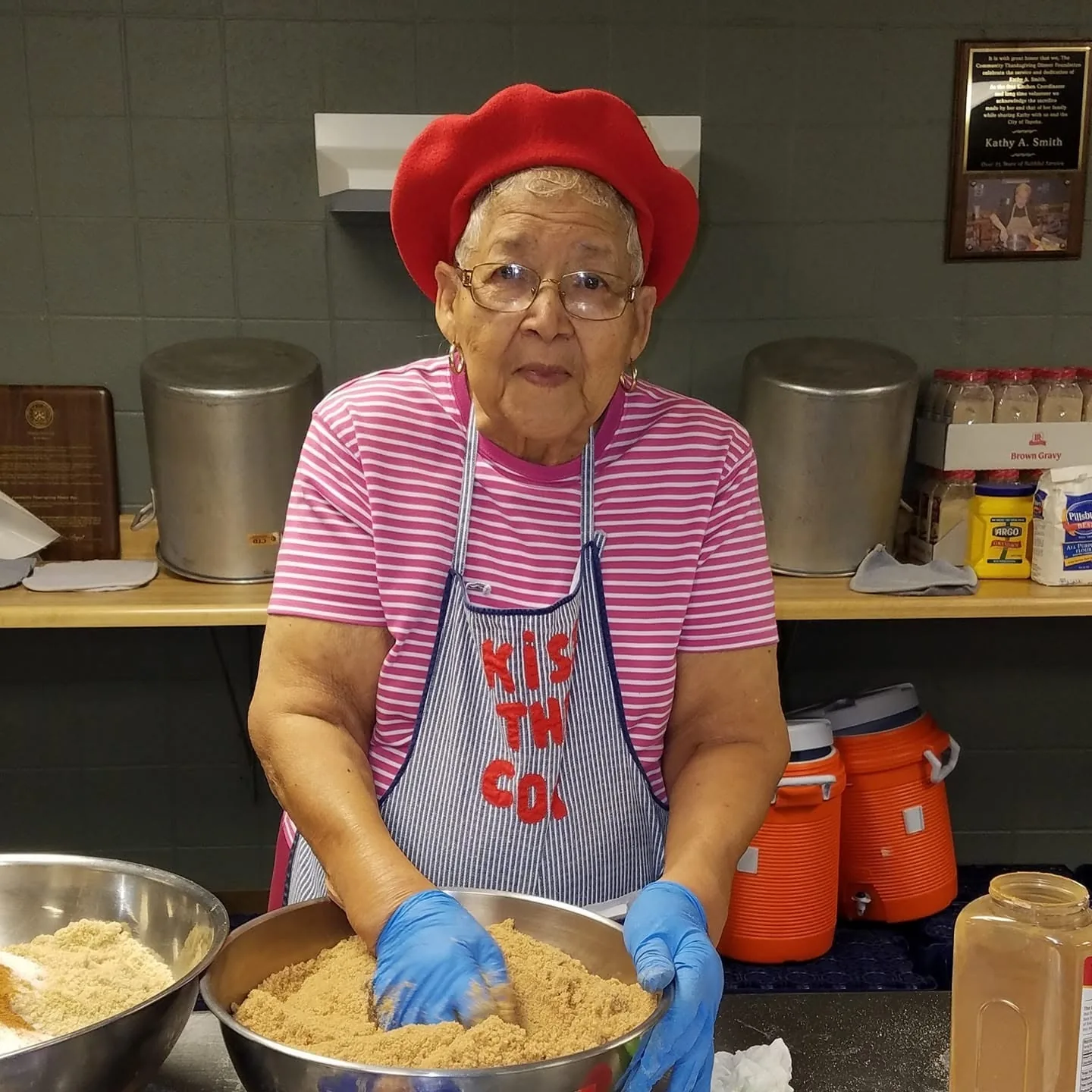 A volunteer in a red hat mixing ingredients in a large bowl.