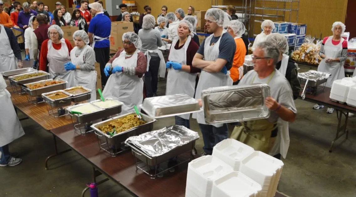 Volunteers readying trays of food together along the Thanksgiving serving line.